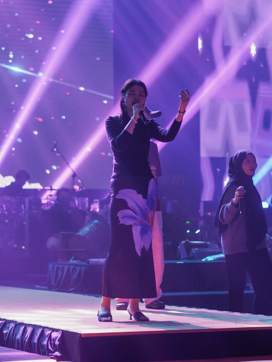 Trisha singing on a stage lit in purple