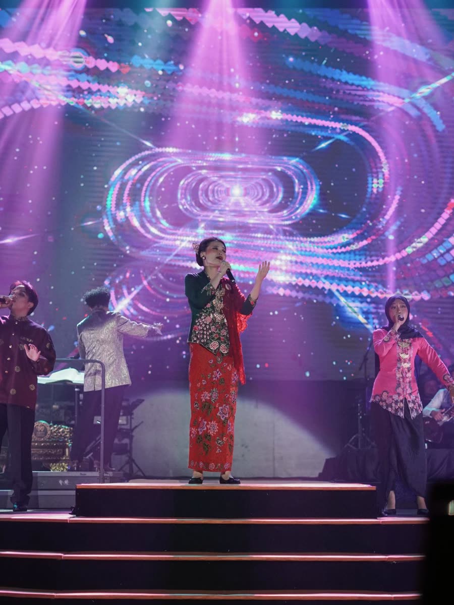 Trisha in a red kebaya on a concert stage